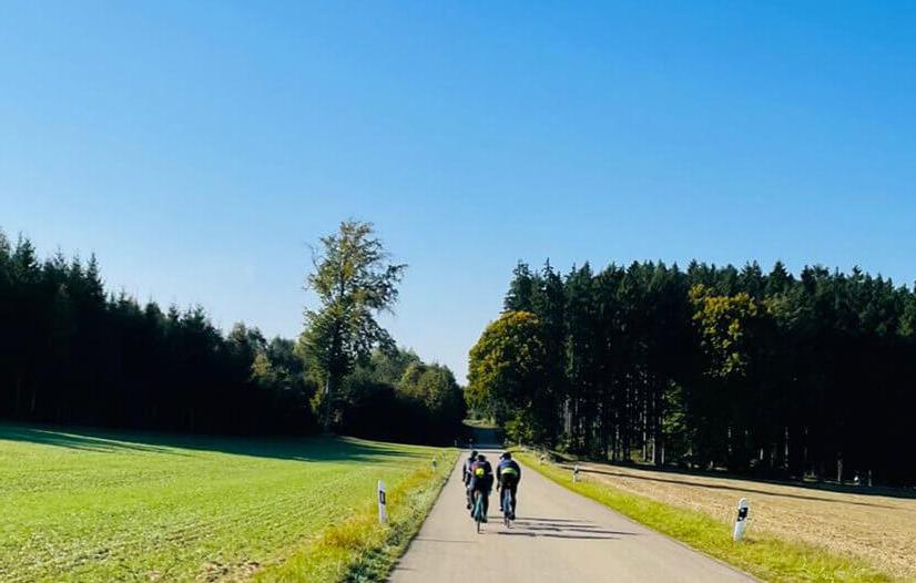 Three cyclists riding an asphalt road through the fields